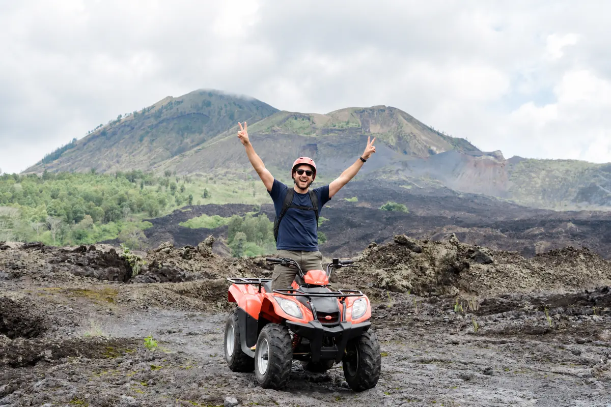 Man seated on an ATV on Mount Batur’s black-lava terrain.