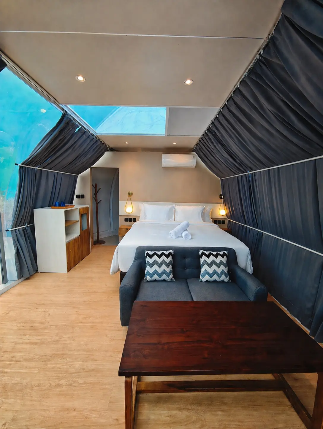 Crystal Nest Suites bedroom with open sky window and warm modern interior.